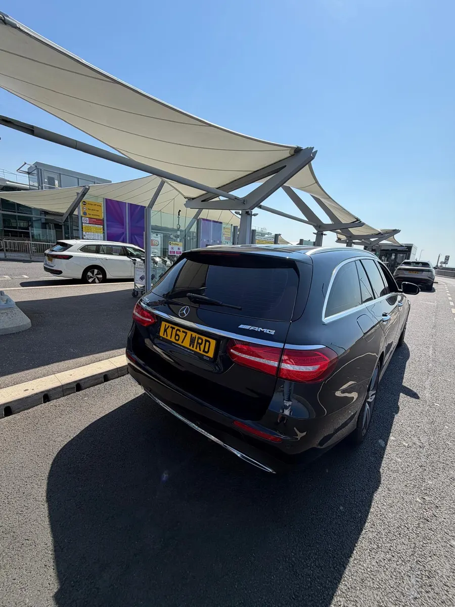 Dark estate car seen from behind under an airport drop-off canopy