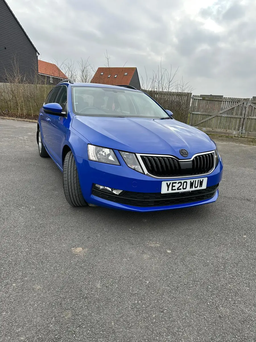 Blue estate car parked by a wooden barn