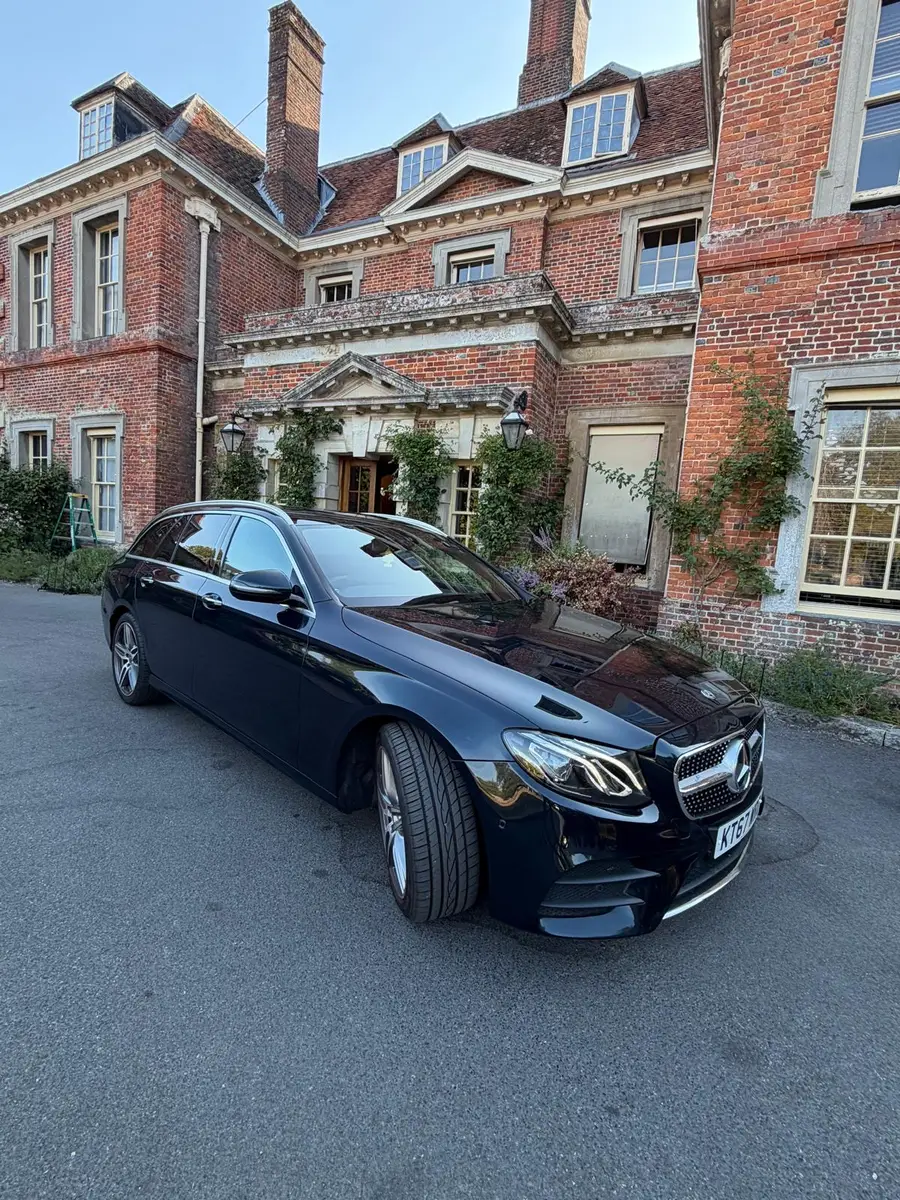 Dark estate car parked in front of a red-brick country house